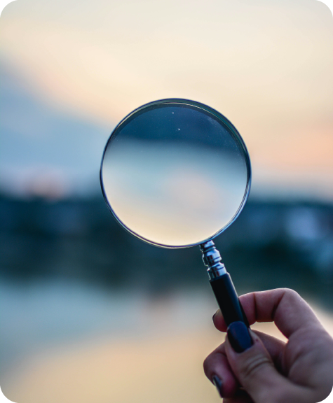 Magnifying glass being held up against setting sun