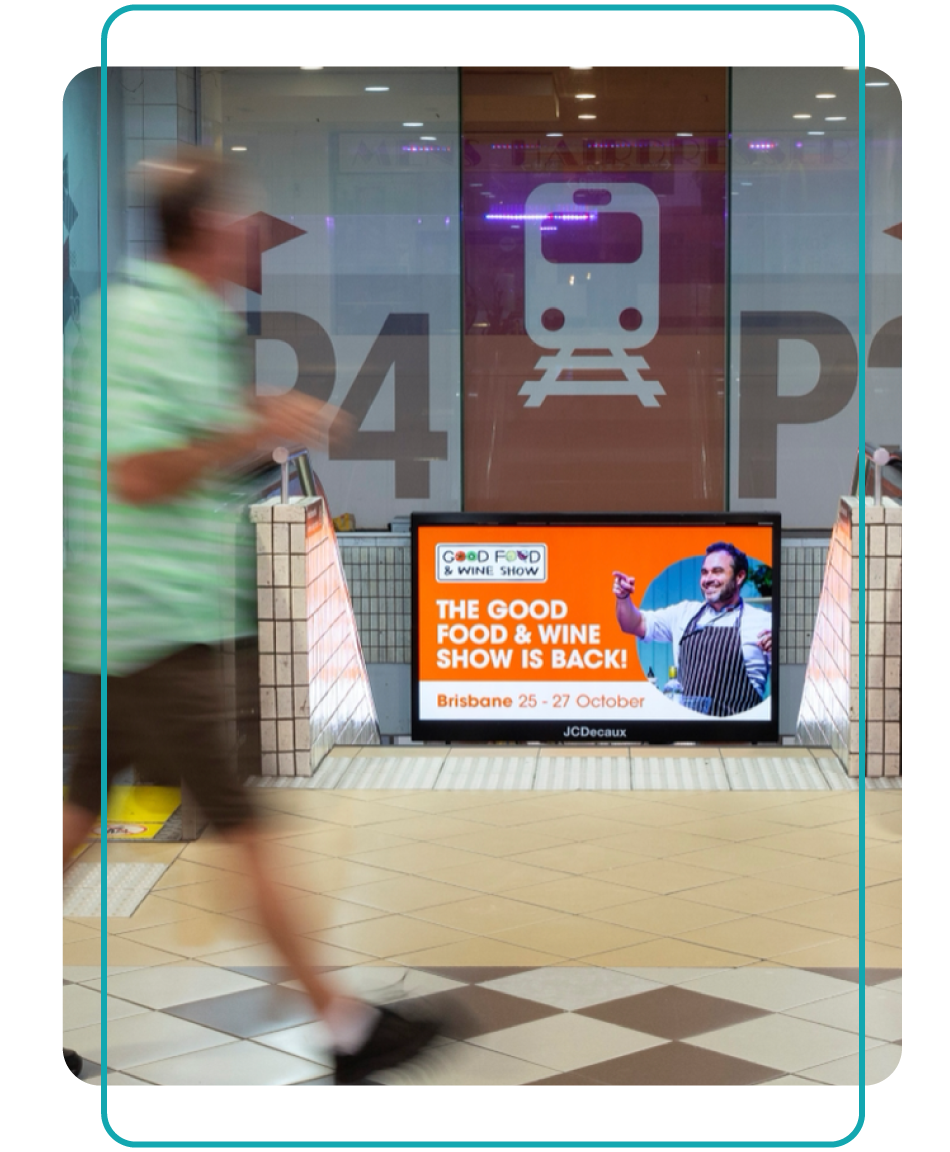 People walk past a digital screen advertisement for Good Food and Wine Festival